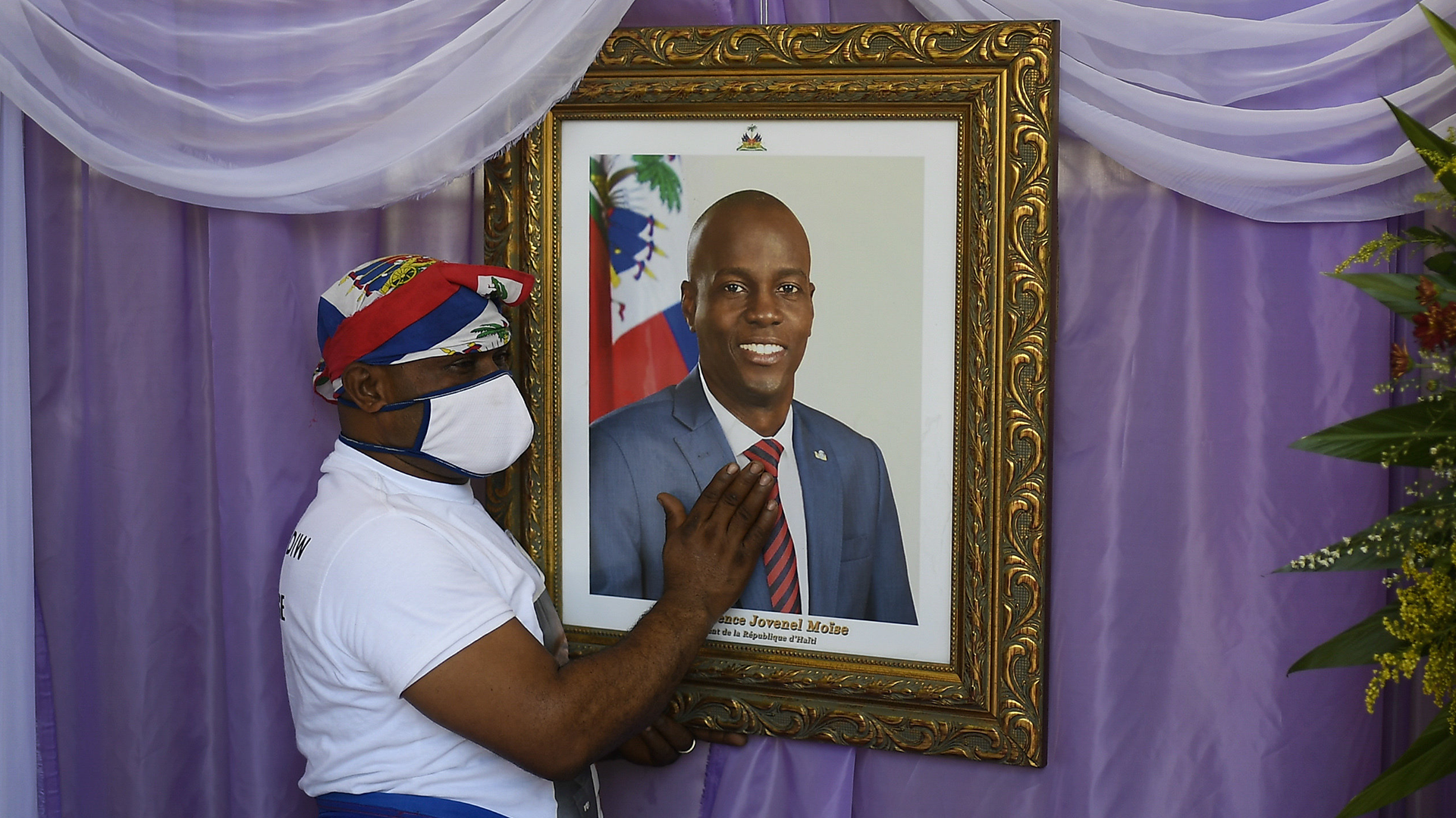 Un homme devant le portrait du président assassiné, Jovenel Moïse.