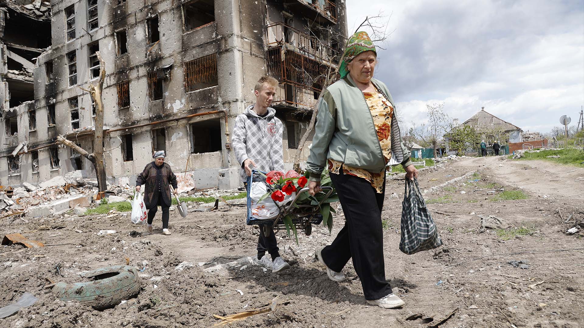 Des femmes passent devant un immeuble détruit à Marioupol, sur le territoire sous le gouvernement de la République populaire de Donetsk, dans l'est de l'Ukraine, le lundi 2 mai 2022. 