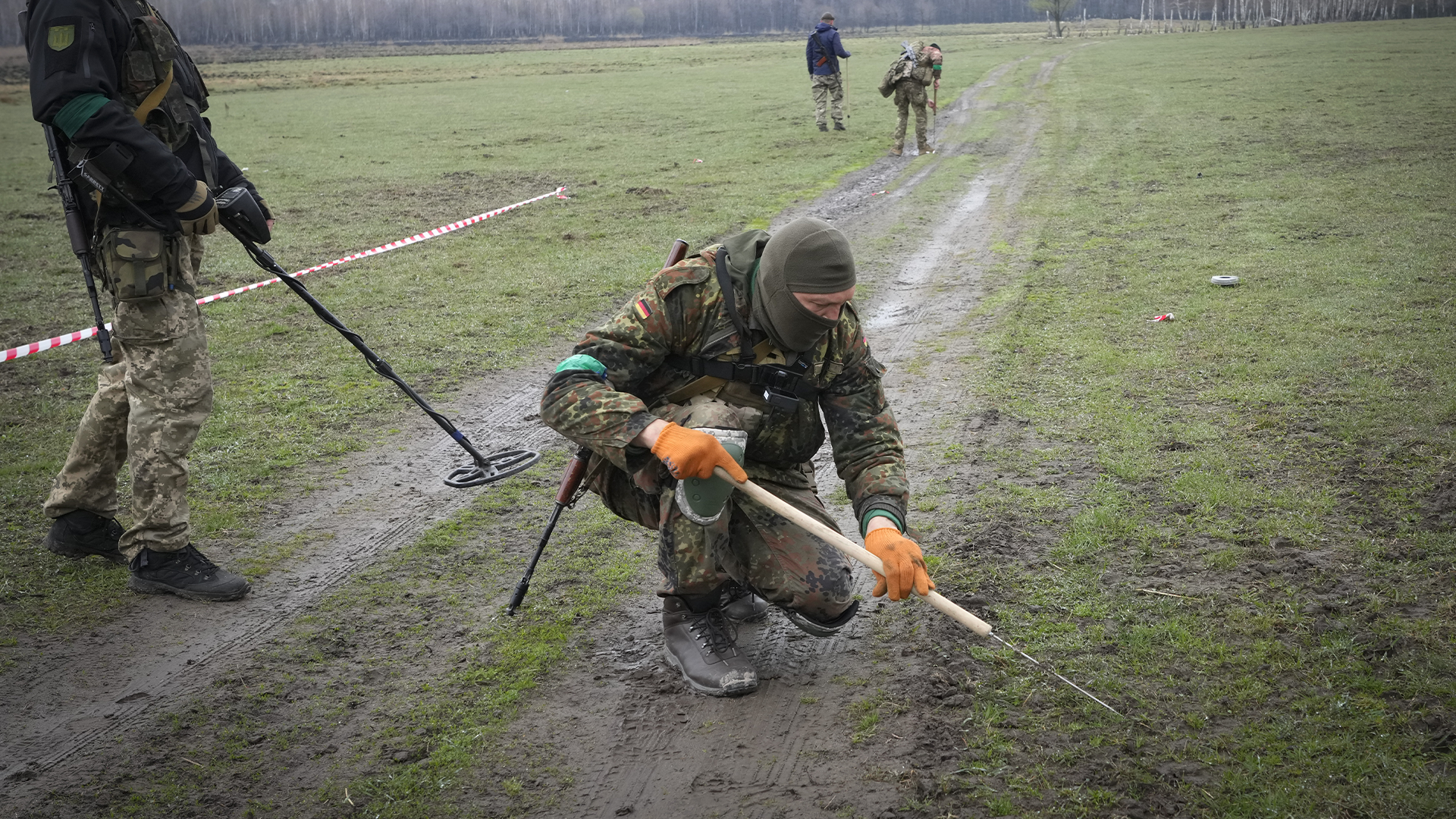Des soldats ukrainiens examinent un champs à la recherche de mines laissées par des soldats russees le 21 avril 2022.