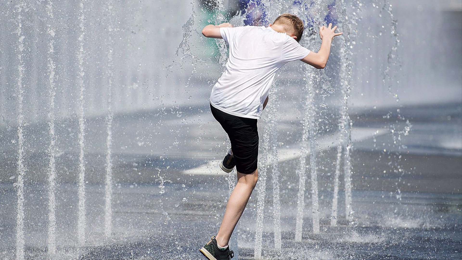 Un garçon se rafraîchit dans une fontaine d'eau alors qu'il combat la chaleur à Montréal, le lundi 2 juillet 2018.