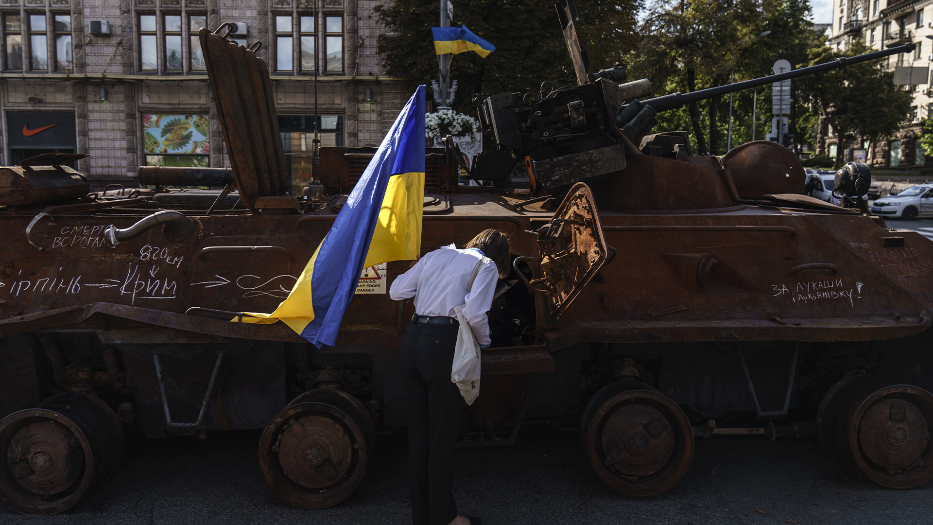 Une femme ukrainienne observe un véhicule militaire russe.