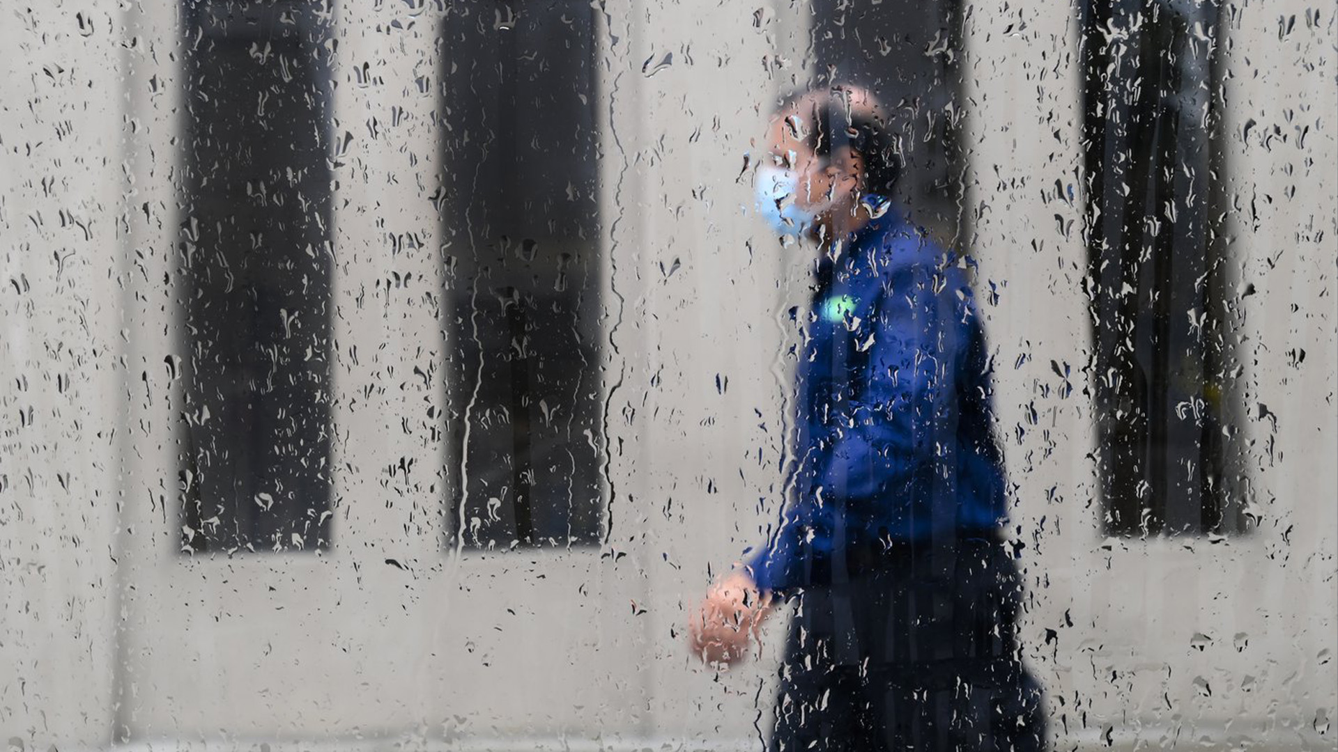 Un piéton marche un jour de pluie tout en portant un masque de protection pendant la pandémie de COVID-19 à Toronto le 18 juin 2021.