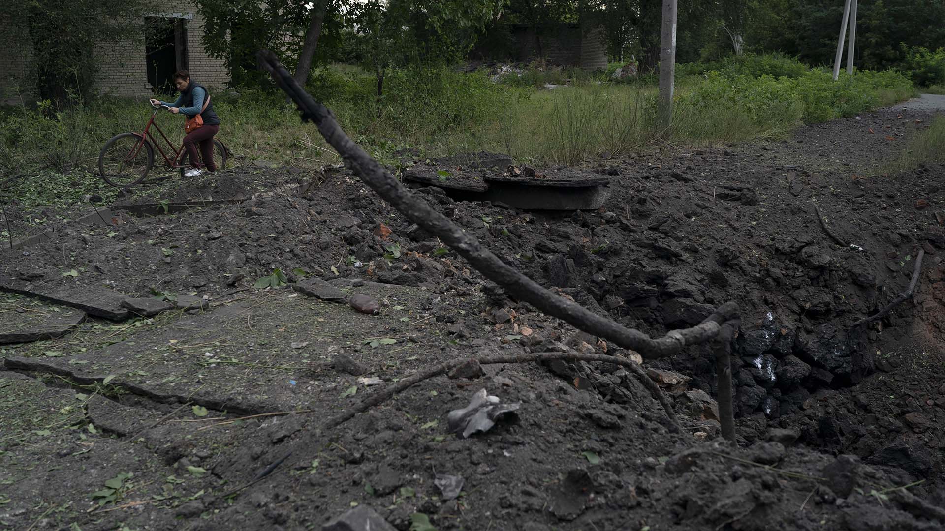 Une femme passe devant un cratère créé par une explosion après une attaque russe dans la région de Pokrovsk, en Ukraine.