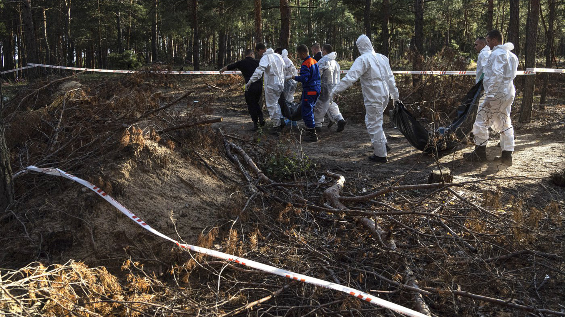 Des secouristes transportent des corps vers un camion frigorifique après leur exhumation dans la zone récemment reprise d'Izium, en Ukraine, le lundi 19 septembre 2022.