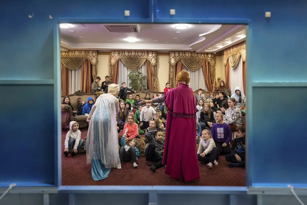 Dans une salle de réunion recouverte de moquette dans ce qui était autrefois un hôtel chic, des enfants ukrainiens crient de bonheur devant un spectacle mis en scène pour eux et face à la joie d'ouvrir des cadeaux.