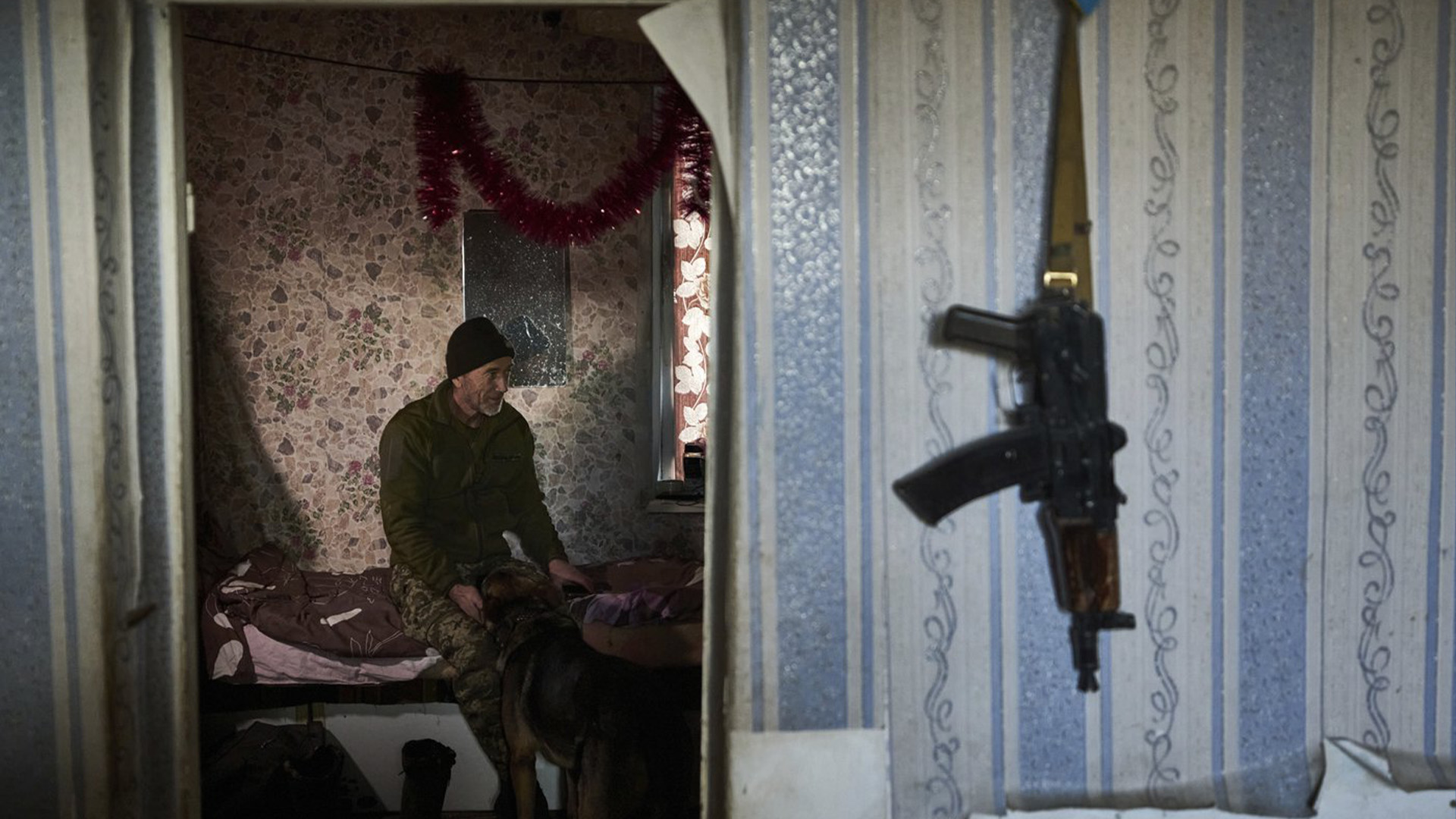 Un soldat ukrainien caresse un chien alors qu'il se repose dans une maison près de Bakhmut, dans la région de Donetsk, en Ukraine, le jeudi 22 décembre 2022.