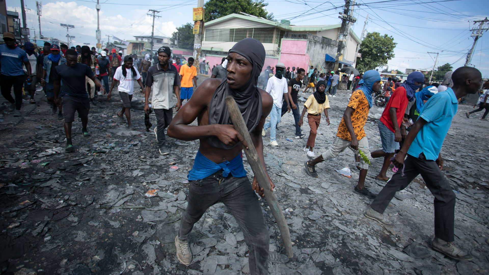 Un manifestant porte un baton de bois comme une arme à feu lors d'une manifestation demandant la résignation de permier ministre par intérim Ariel Henry.