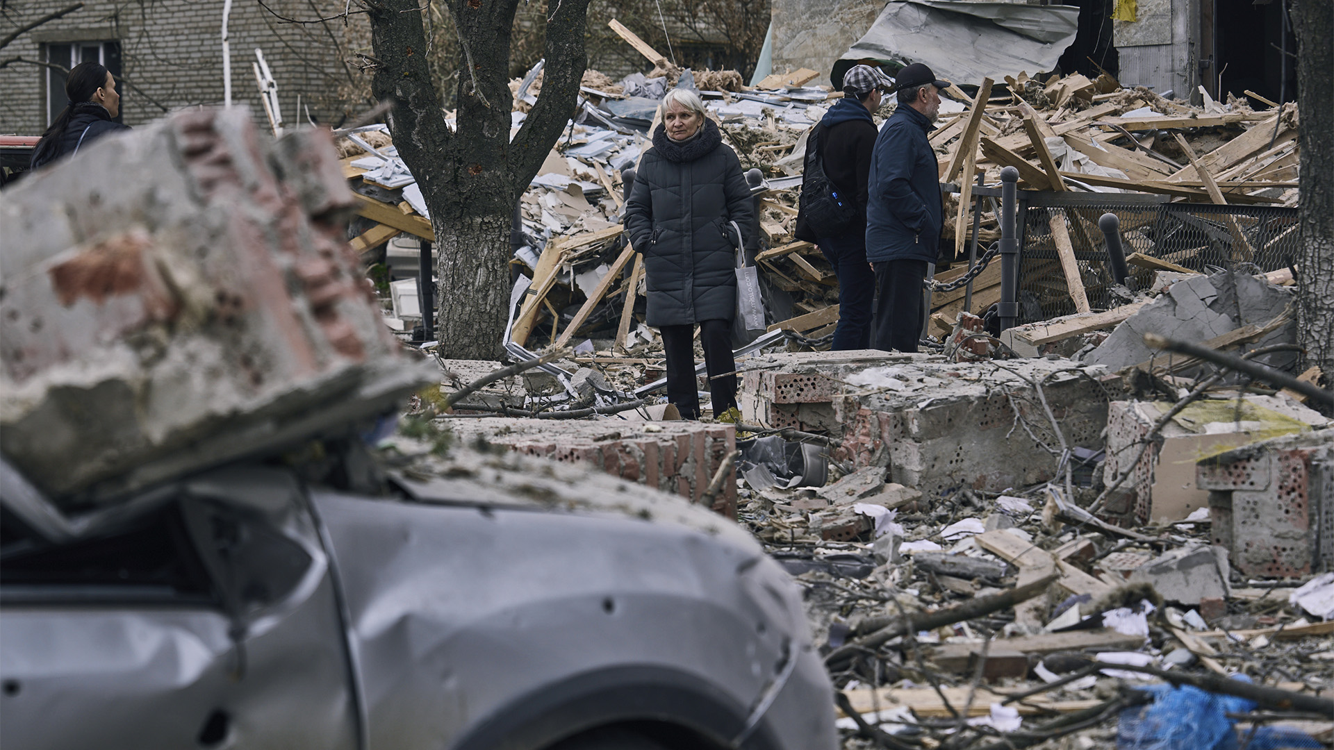 Des personnes se tiennent devant un bâtiment fortement endommagé après une attaque russe à Sloviansk, dans la région de Donetsk, en Ukraine, le lundi 27 mars 2023. 