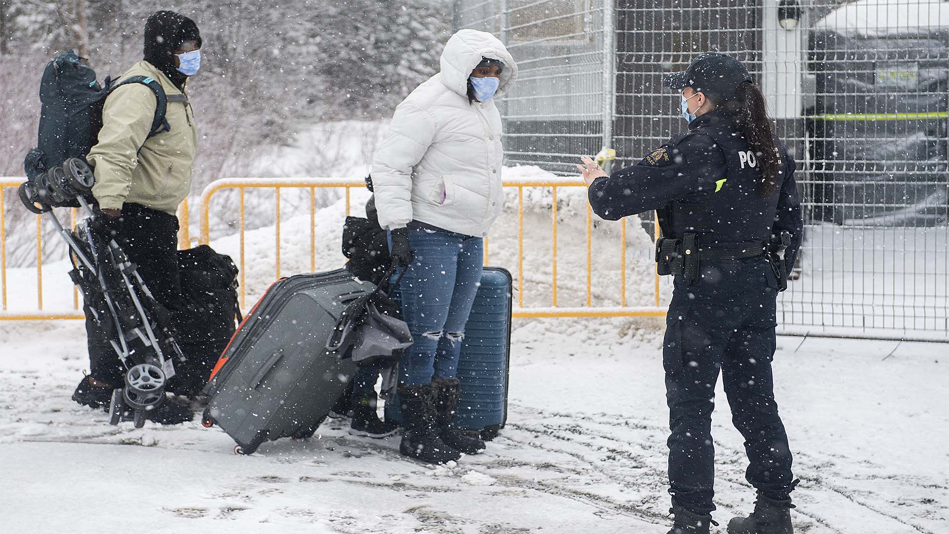 Un agent de la GRC arrête des personnes alors qu'elles entrent au Canada par le chemin Roxham à la frontière canado-américaine à Hemmingford, au Québec, le samedi 25 mars 2023. 