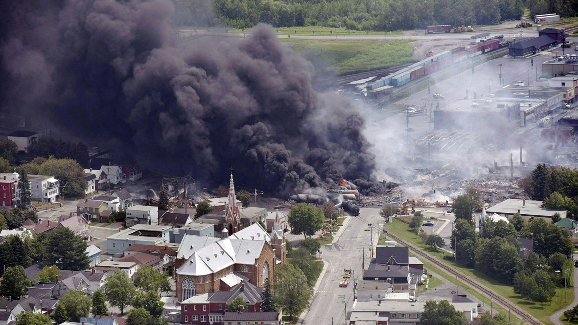 Dans cette photo d'archive du 6 juillet 2013, de la fumée s'élève de wagons transportant du pétrole brut après avoir déraillé au centre-ville de Lac Mégantic, au Québec.