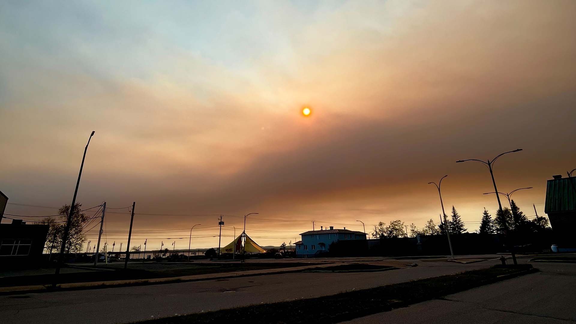 Une photo du centre-ville de Sept-Îles où l'on voit de la fumée dans le ciel, le 3 juin 2023 en fin de journée.