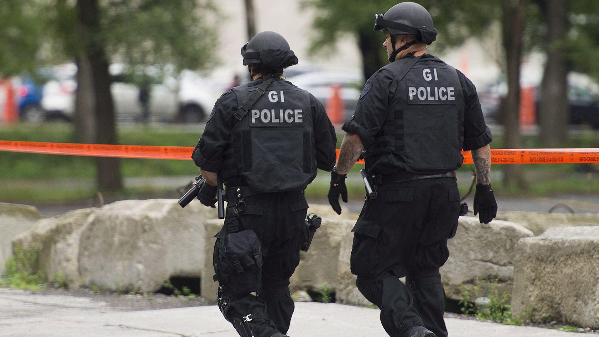 Des policiers armés surveillent la scène près du Square-Victoria à Montréal, le 14 juillet 2017 où un homme se trouverait dans une voiture armé d'un couteau.