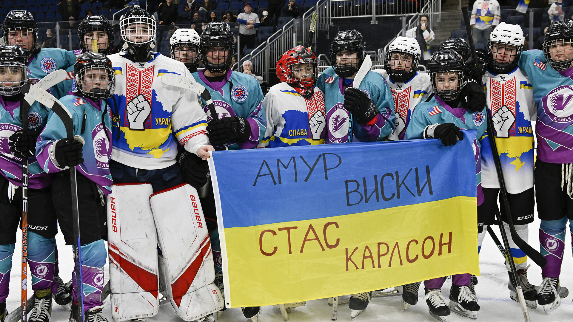 Des joueurs de l'équipe d'Ukraine (en blanc) et des Flames de l'Académie du Vermont posent ensemble pour une photo après un match du Tournoi international de hockey pee-week de Québec, en février 2023.