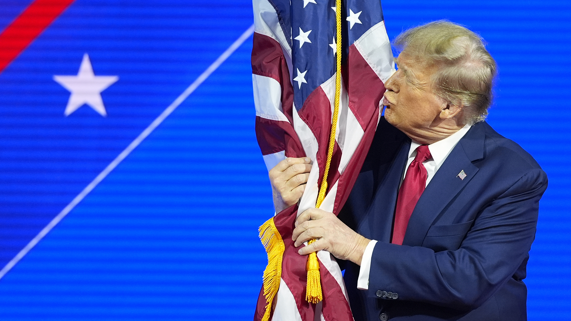 Donald Trump embrasse un drapeau américain dans une conférence au Maryland le 24 février 2024.