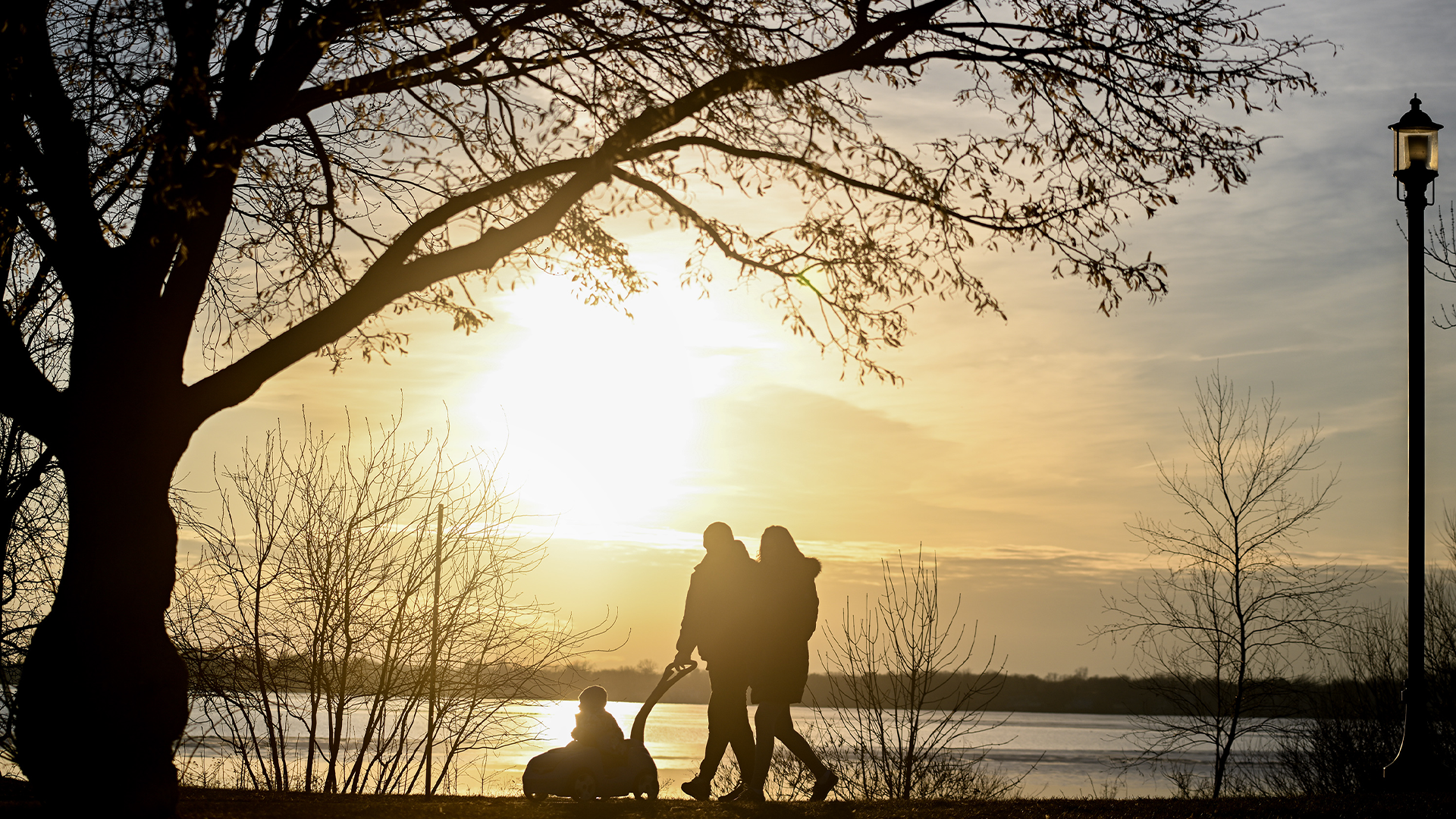 Le soleil se couche derrière une famille qui marche le long du lac Saint-Louis à Montréal, le dimanche 3 mars 2024, par une douce journée d'hiver.