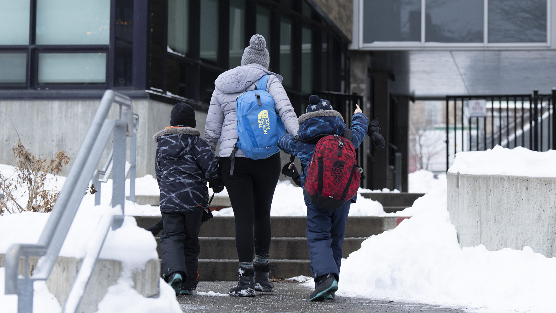 Une mère accompagne ses enfants à l'entrée d'une école de Montréal en janvier 2024.