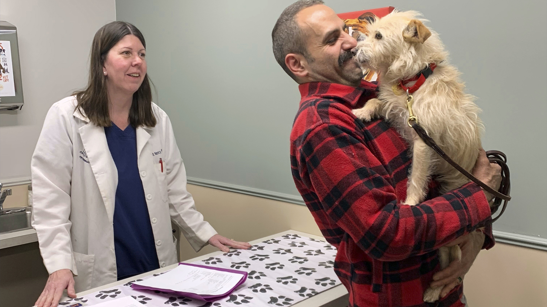 Dans cette image fournie par Corinne Martin, Mehrad Houman tient sa chienne, Mishka, après qu'elle ait été examinée par la vétérinaire Nancy Pillsbury à Harper Woods, Michigan, vendredi 29 mars 2024. Mishka a été découverte dans la banlieue de Détroit, huit mois après avoir disparu à San Diego.