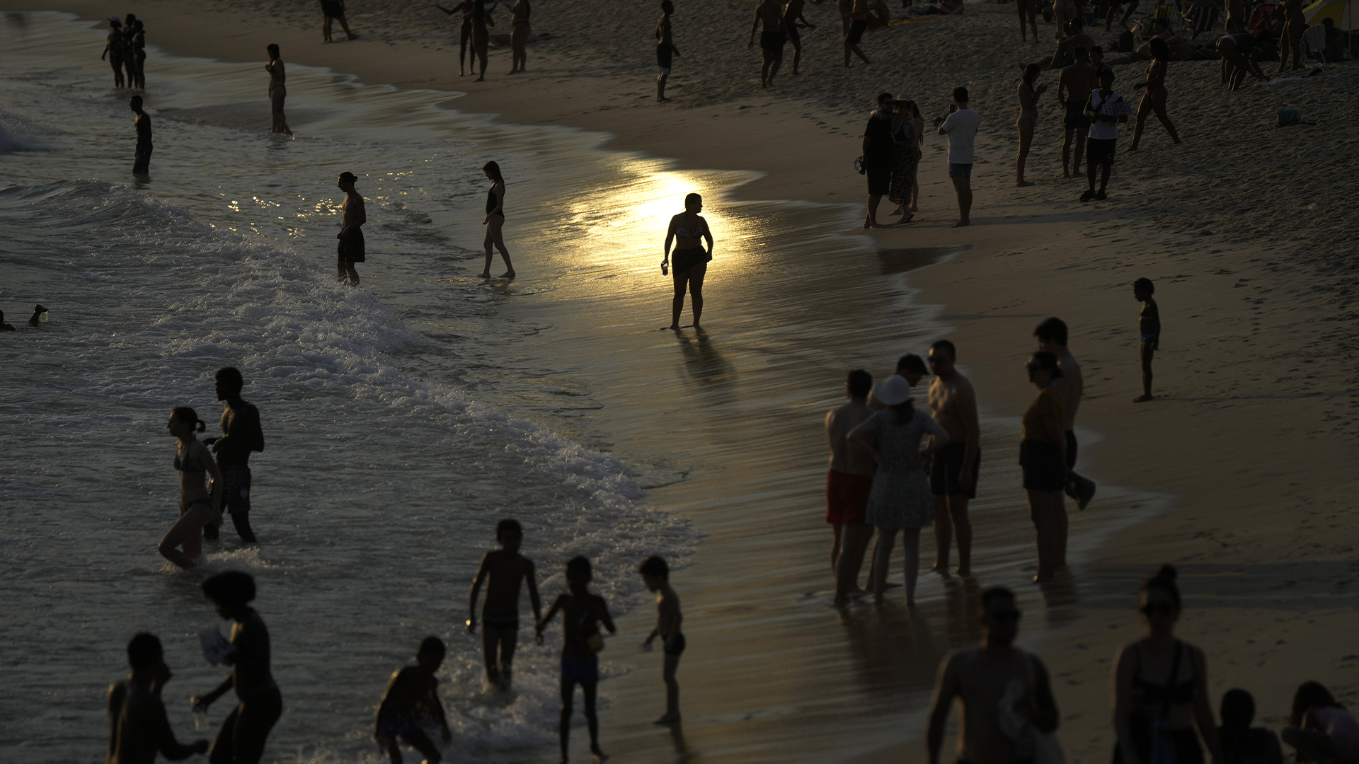 Des gens traînent le long du rivage de la plage d’Arpoador au milieu d’une vague de chaleur, à Rio de Janeiro, au Brésil, le mercredi 20 mars 2024.