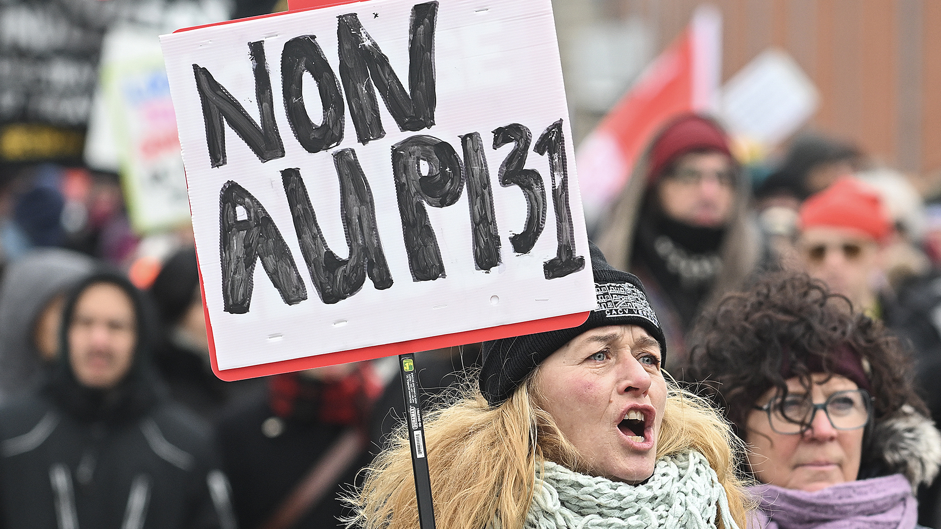 Une femme brandit une pancarte dans une manifestation contre le projet de loi 31 à Montréal en février 2024.