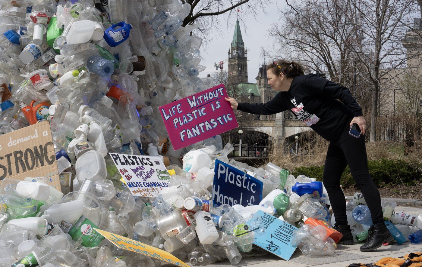 La militante Dianne Peterson place une pancarte sur une installation d'art public à l'extérieur d'une conférence des Nations unies sur les déchets plastiques, le mardi 23 avril 2024 à Ottawa. 