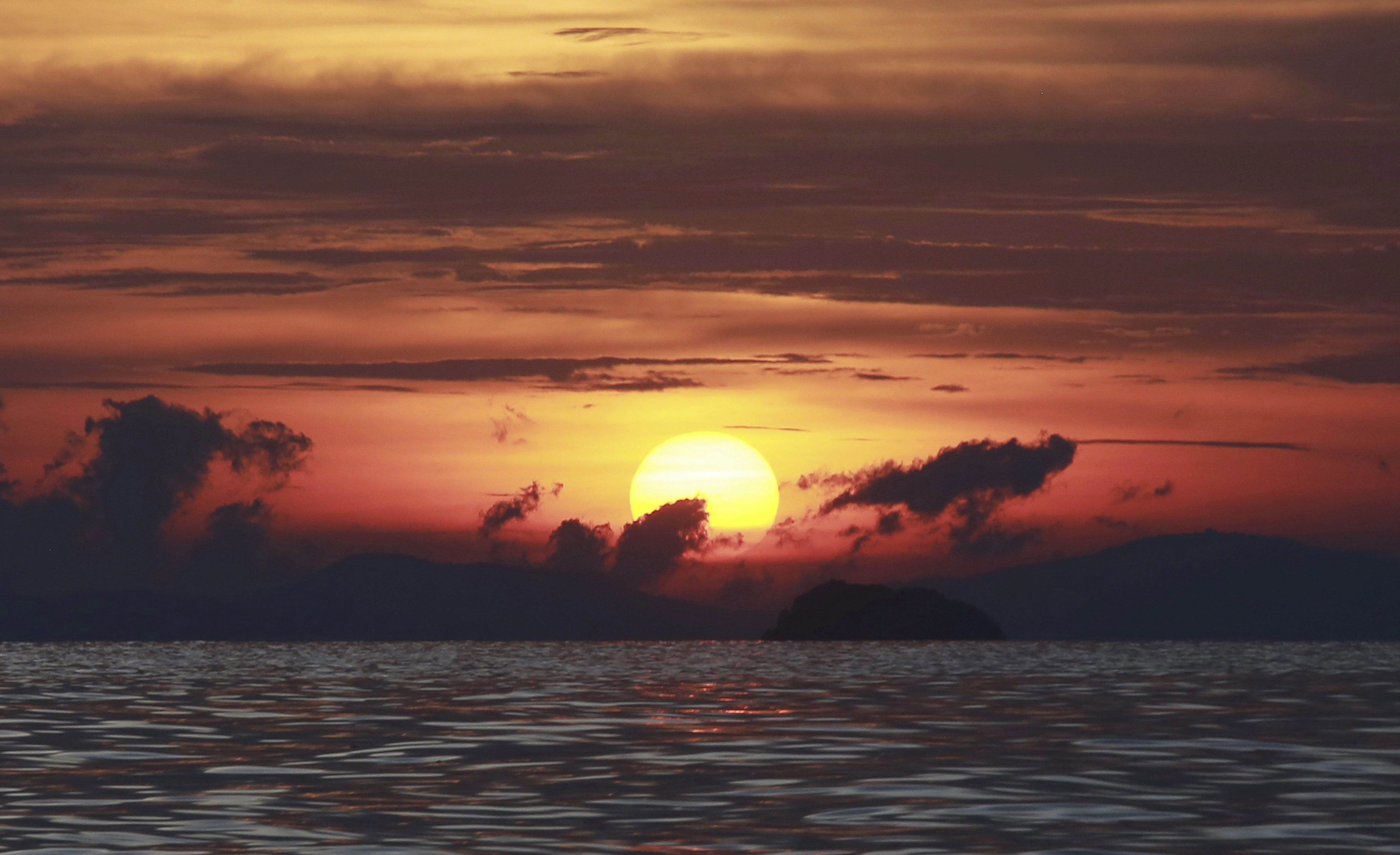 The sun sets in front of Maya Bay on Phi Phi Leh island, Krabi province, Thailand, Thursday, May 31, 2018. Maya Bay on Phi Phi Leh Island in the Andaman Sea will close to tourists for four months from Friday to give its coral reefs and sea life a chance to recover from an onslaught that began nearly two decades ago. (AP Photo/Sakchai Lalit)