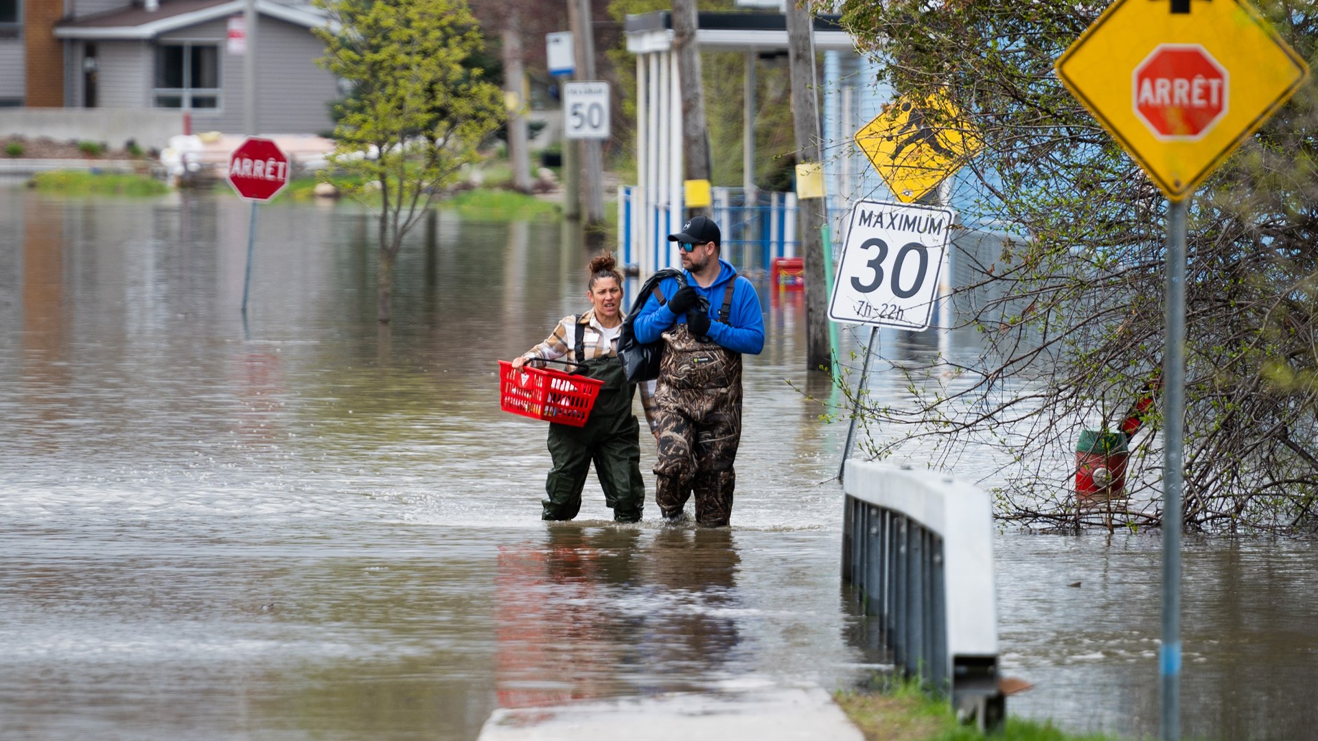 Des résidants se dirigent vers la terre ferme à la suite des inondations dans la région de Gatineau, au Québec, le jeudi 4 mai 2023.