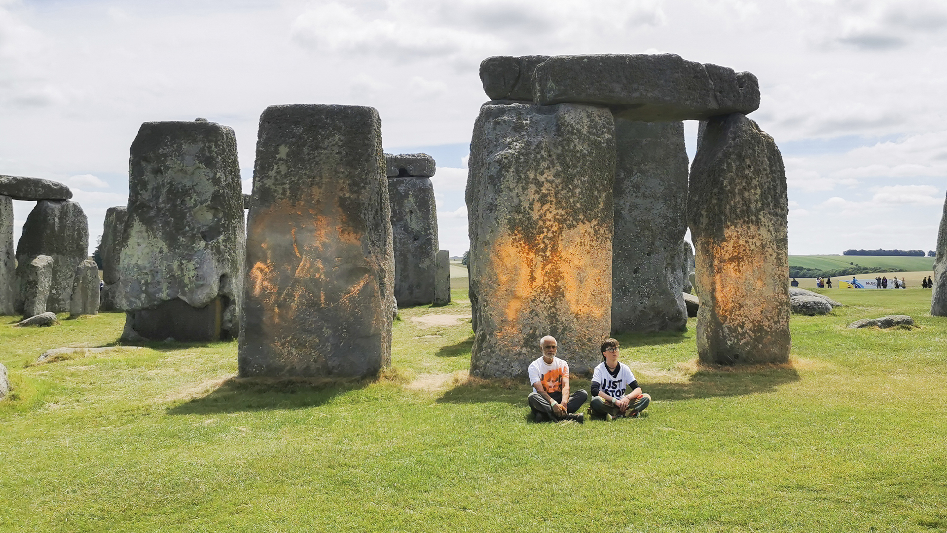 Cette photo fournie par Just Stop Oil montre des militants du groupe assis après avoir pulvérisé une substance orange sur Stonehenge, à Salisbury, en Angleterre, le mercredi 19 juin 2024.