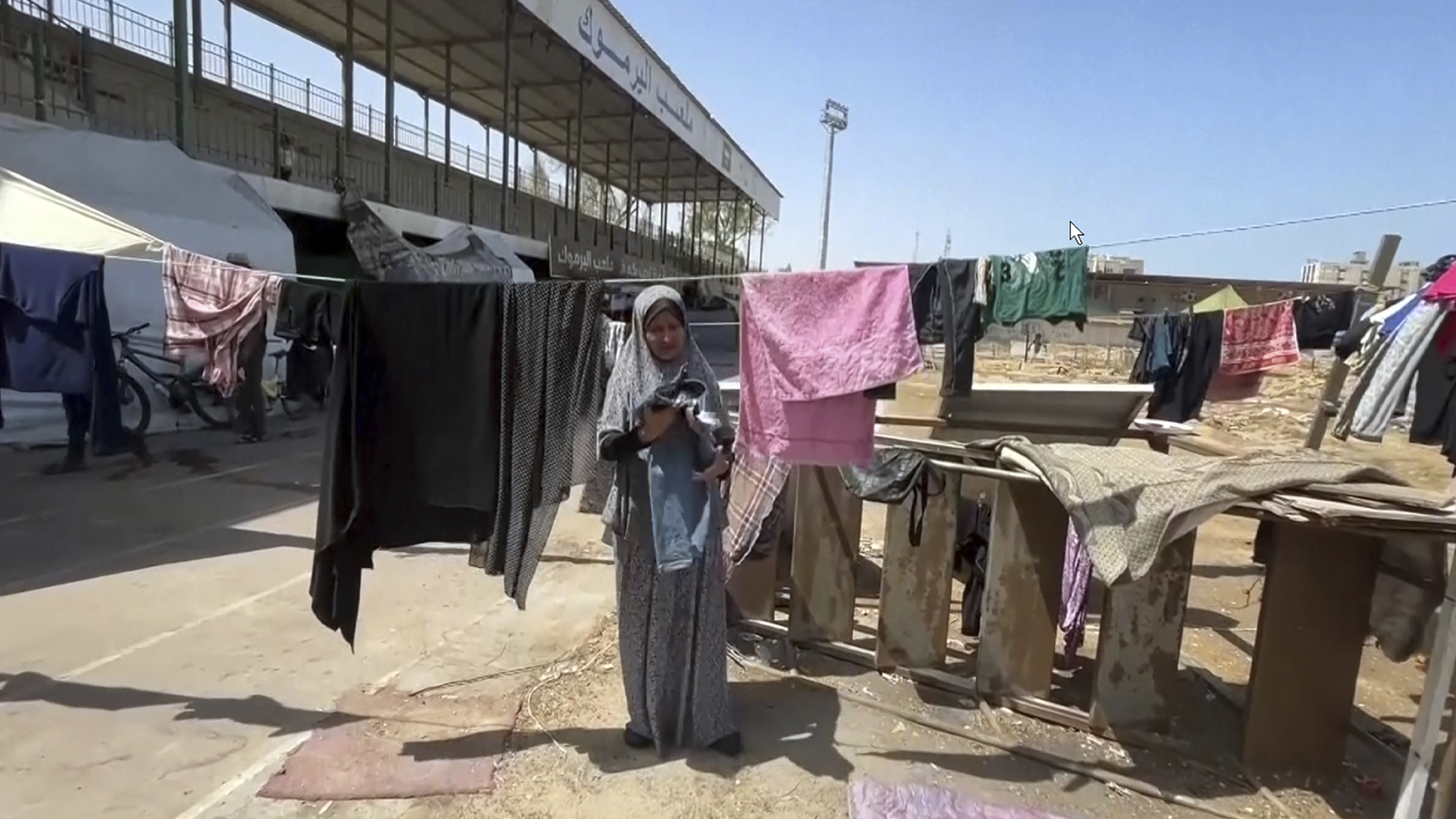 Cette image tirée d'une vidéo montre une femme séchant des vêtements, le vendredi 5 juillet 2024, dans la ville de Gaza.