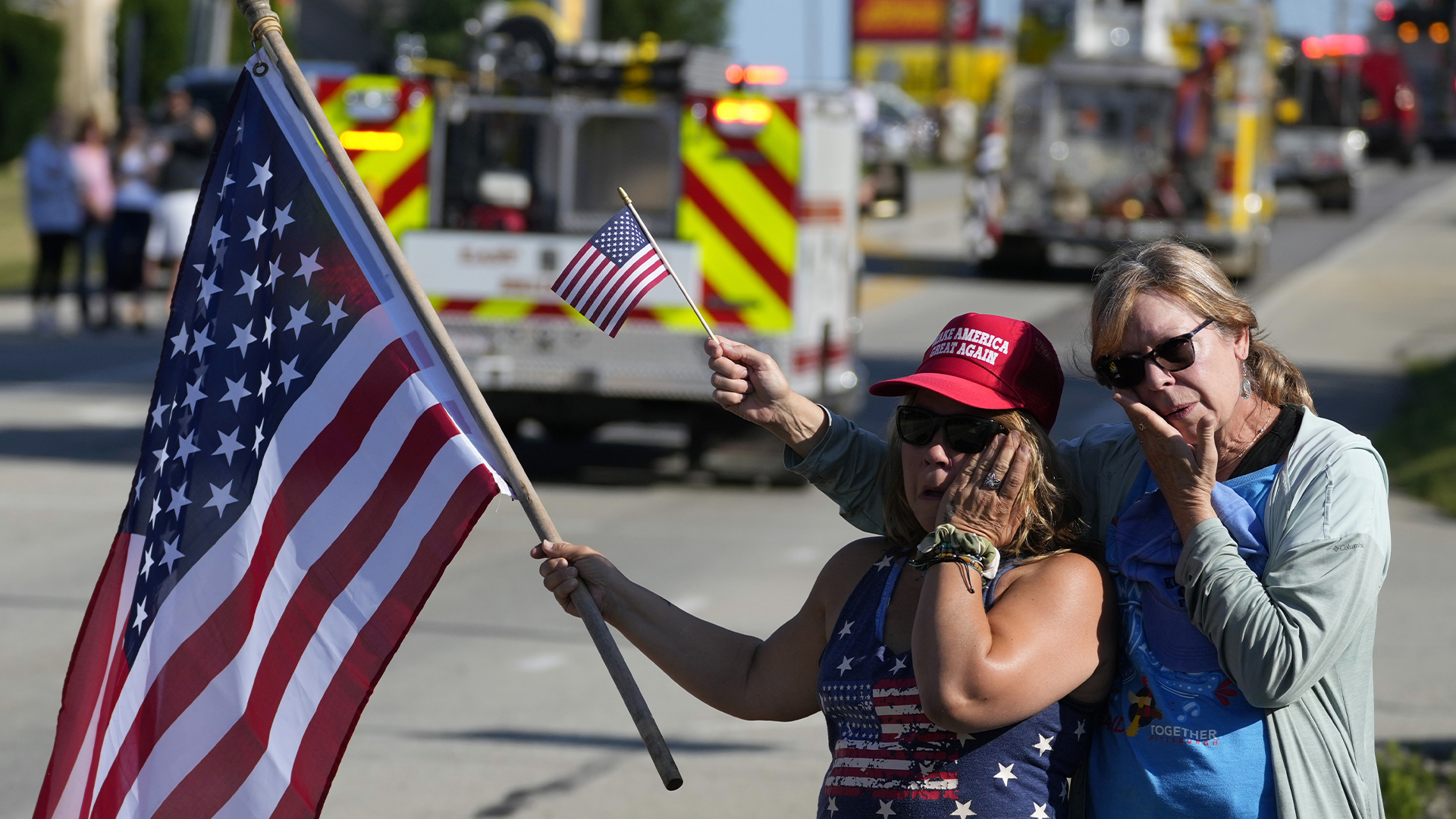 Merri Cambo, à gauche, de Saxonburg, en Pennsylvanie, et son amie Jane Wesolosky, de Buffalo, en Pennsylvanie, réagissent au passage du cortège funèbre de Corey Comperatore, le vendredi 19 juillet 2024, à Sarver, en Pennsylvanie. Comperatore, un ancien chef des pompiers, a été tué par balle alors qu'il participait à un rassemblement du week-end en faveur de l'ancien président Donald Trump. 