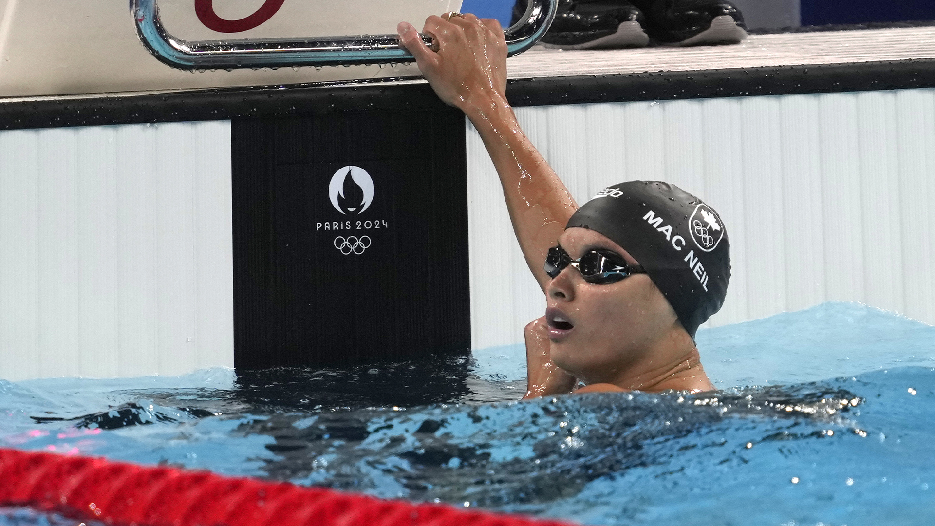 Maggie Mac Neil, du Canada, regarde l'horloge pour trouver son temps après avoir participé à la demi-finale du 100 mètres papillon féminin aux Jeux olympiques d'été de 2024, le samedi 27 juillet 2024, à Nanterre, en France. 