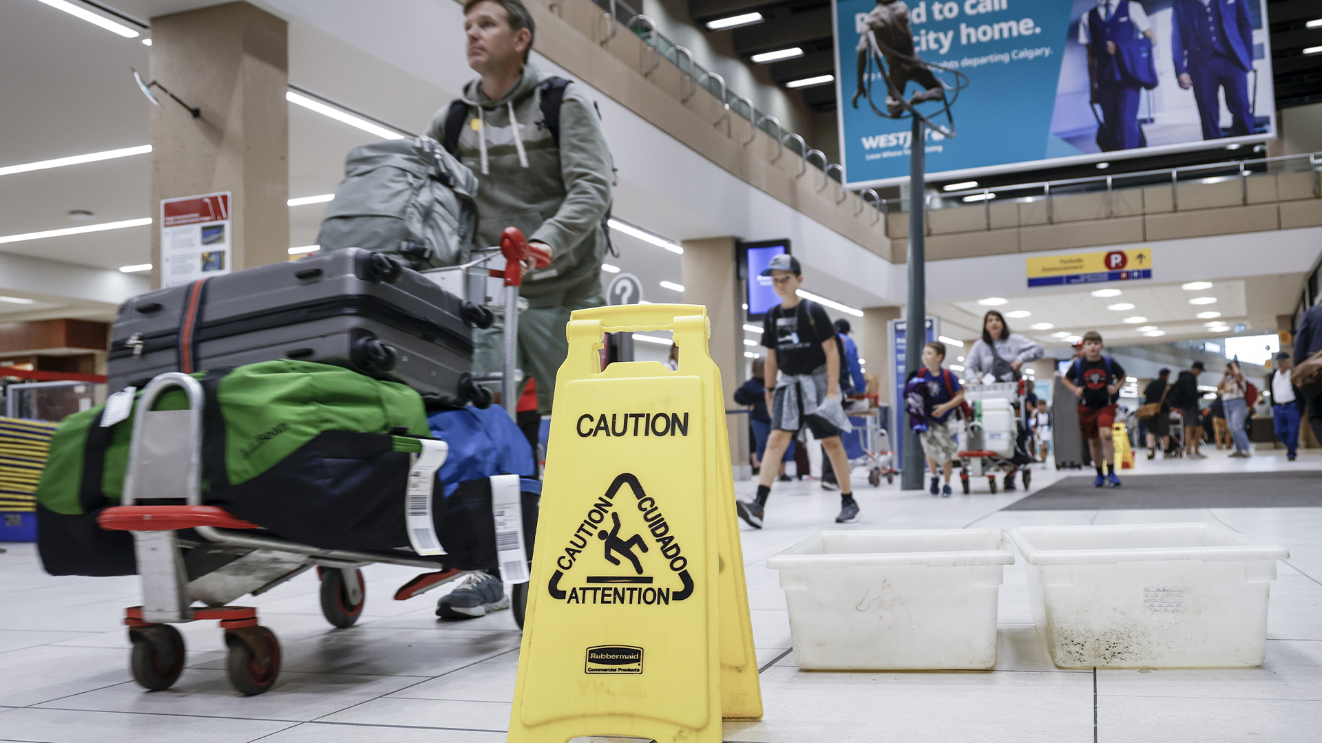 Des voyageurs manœuvrent autour des seaux déposés pour les fuites alors que des réparations sont en cours à l'aéroport international de Calgary, le mardi 6 août 2024. 