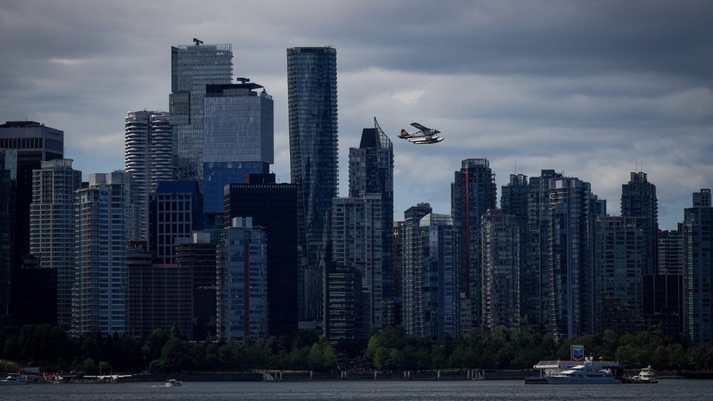 Un hydravion de Harbour Air décolle devant des tours de bureaux et de condominiums alors qu'un bateau fait le plein à une station flottante de Chevron sur l'eau, à Vancouver, le 25 juillet 2024. 