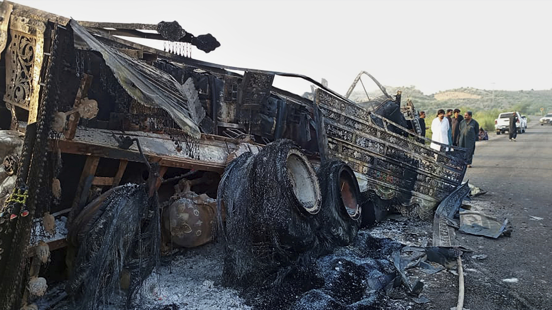 Des gens regardent un véhicule brûlé par des hommes armés après avoir tué des passagers sur une autoroute à Musakhail, un district de la province du Baluchistan dans le sud-ouest du Pakistan, lundi 26 août 2024. 