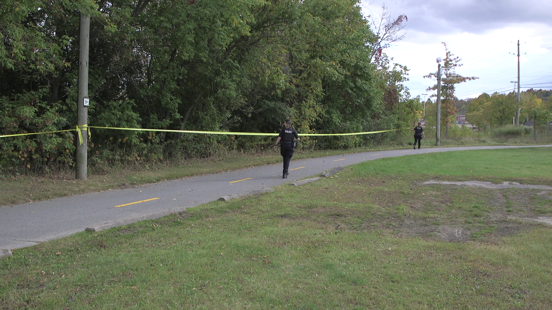 Des policières marchent à proximité d'un périmètre de sécurité relié à la découverte d'un corps non loin de la rivière Saint-François, le 1er octobre 2024 à Sherbrooke.