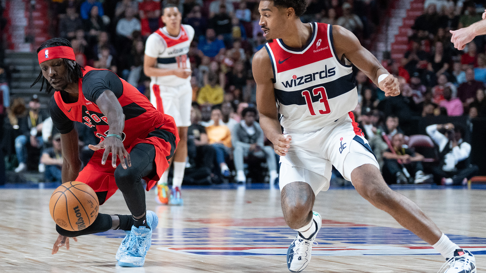 L'attaquant des Raptors de Toronto Chris Boucher (25) tente de contrôler le ballon contre le garde des Wizards de Washington Jordan Poole (13) lors de la première moitié de l'action de basket-ball de pré-saison de la NBA à Montréal, le dimanche 6 octobre 2024. 