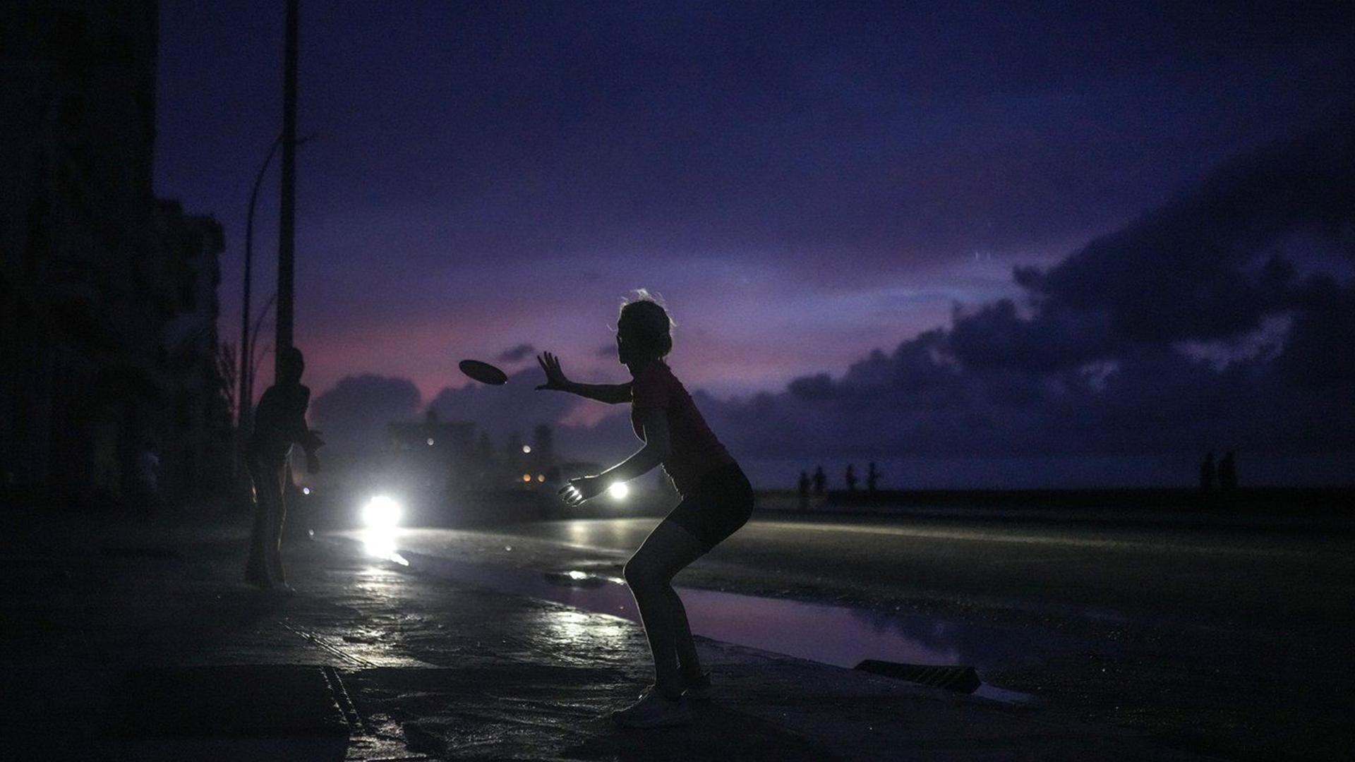 Une femme se prépare à attraper un frisbee lancé pendant une panne d'électricité massive après la défaillance d'une grande centrale électrique à La Havane, à Cuba, le vendredi 18 octobre 2024.