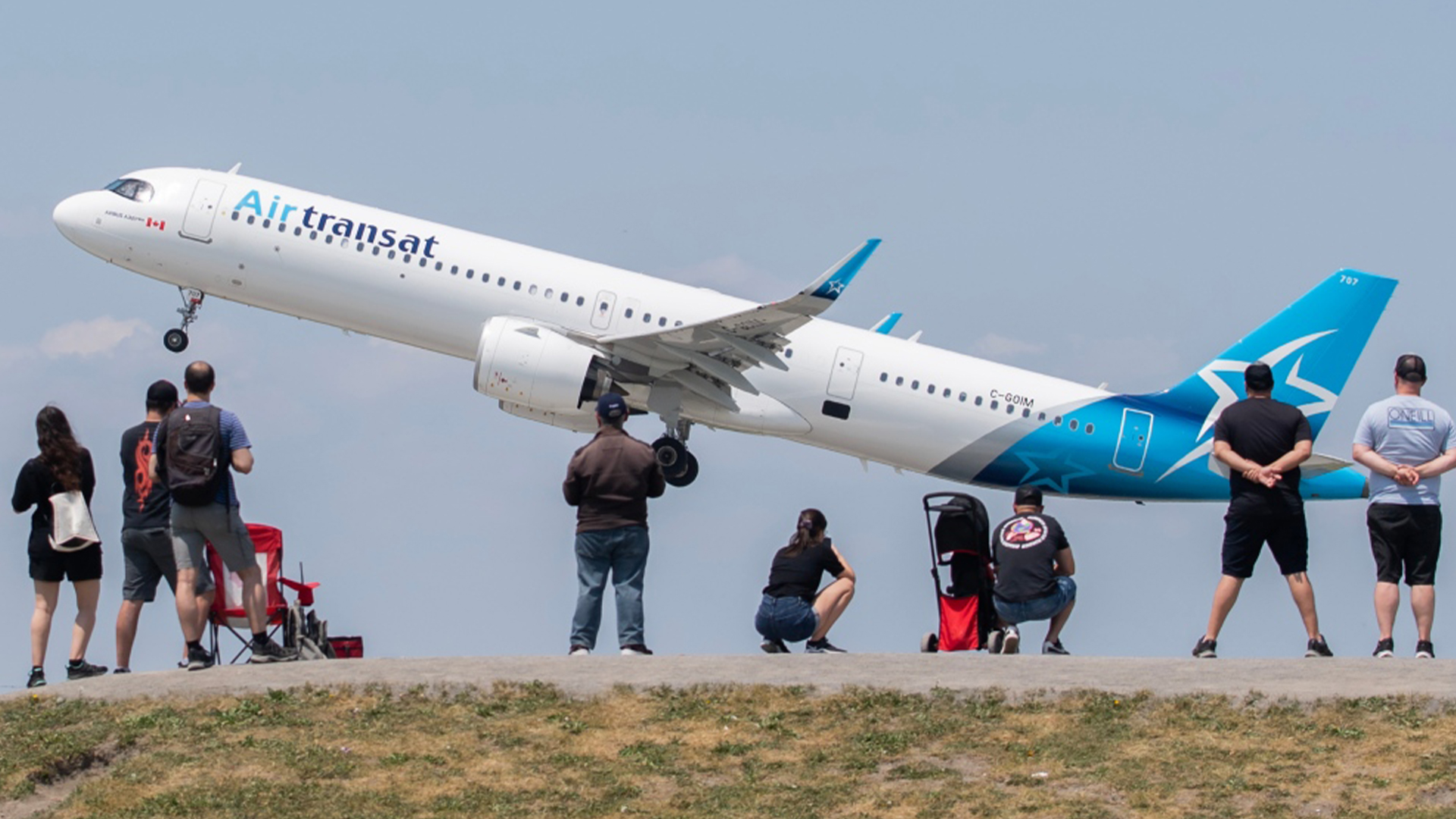 Des gens regardent un avion d'Air Transat décoller à l'aéroport international Montréal-Trudeau, le 11 juin 2023.