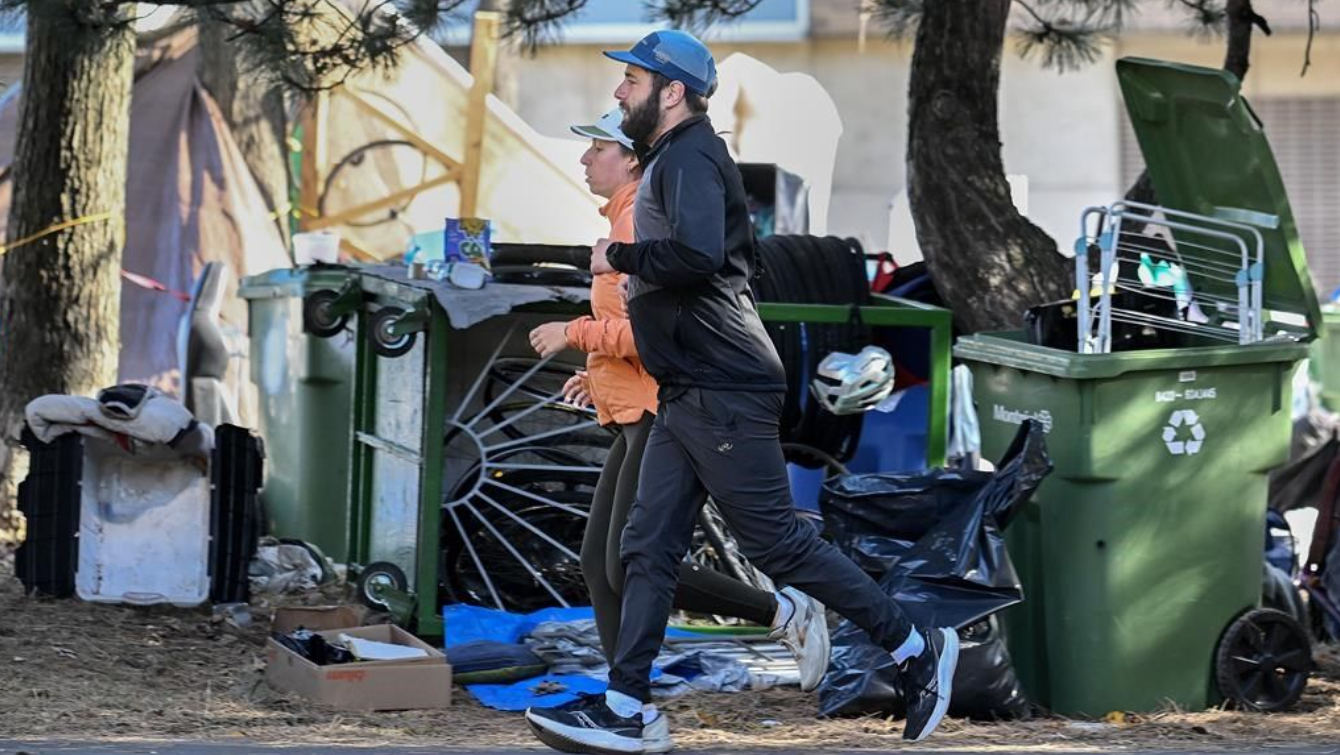 Des coureurs passent devant un campement d'itinérants dans l'est de Montréal, le 25 octobre 204. 