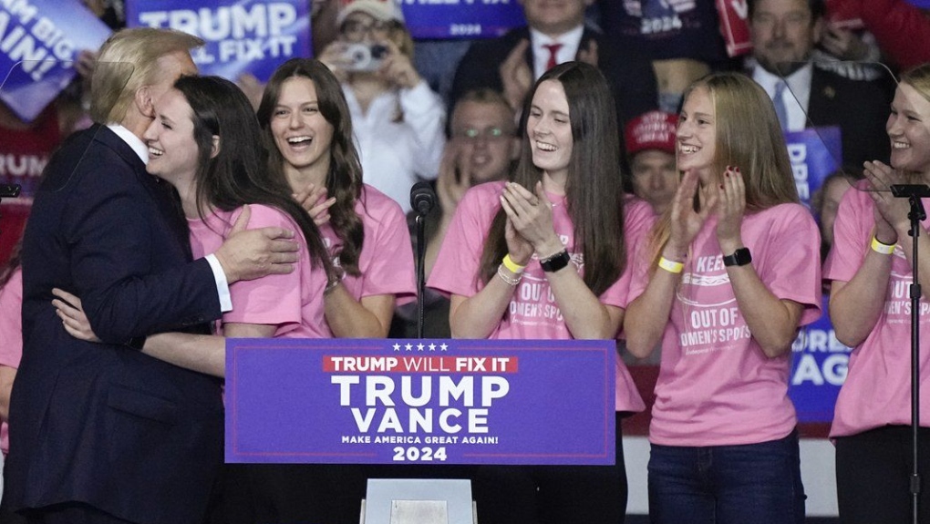 Lilly Mullens, de l'équipe de natation du Roanoke College, est serrée dans les bras du candidat républicain à la présidence, l'ancien président des États-Unis Donald Trump, lors d'un rassemblement de campagne, samedi 2 novembre 2024, à Salem, en Virginie. 