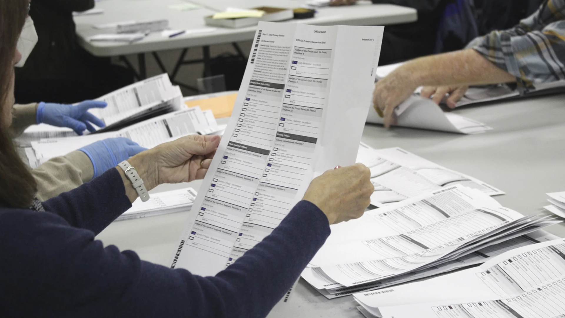  Un agent électoral examine un bulletin de vote, le 19 mai 2022, à Oregon City. 