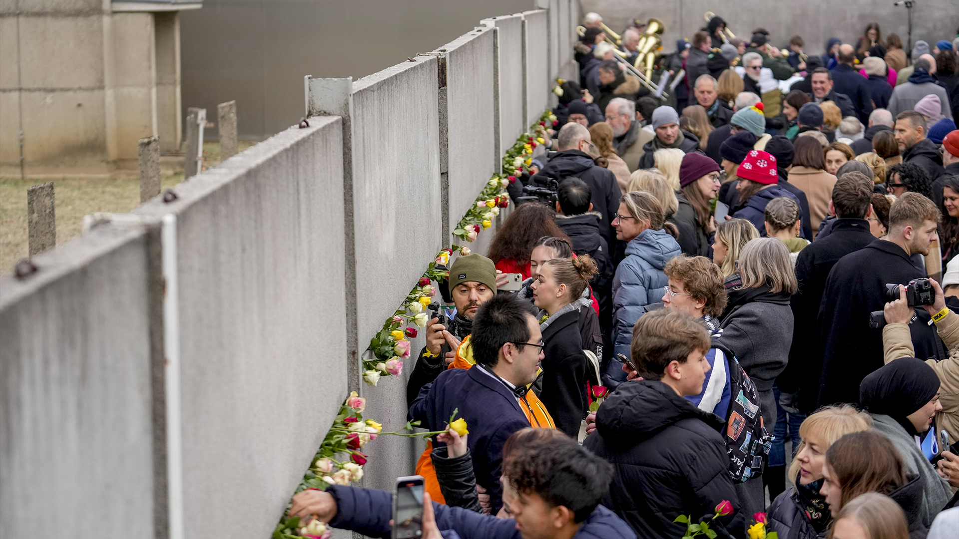 Des personnes assistent à une cérémonie de dépôt de fleurs à l’occasion du 35e anniversaire de la chute du mur sur le terrain du Mémorial du mur de Berlin, à Berlin, en Allemagne, le samedi 9 novembre 2024. 