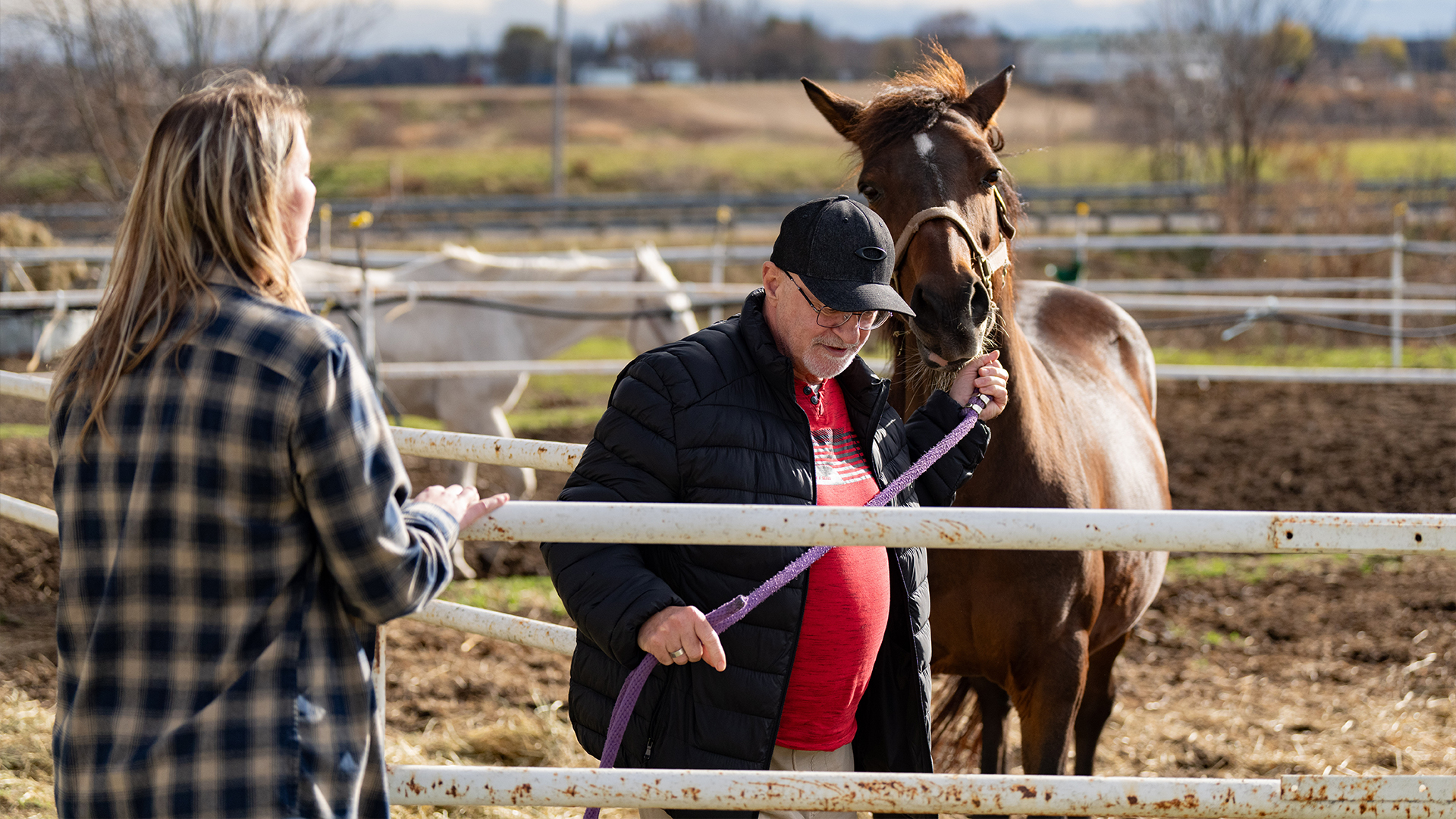 La travailleuse sociale Marie-Pier Dusseault regarde Christian, un vétéran des Forces armées canadiennes, sortir un cheval à Equi-Sens, un programme qui intègre les chevaux comme moyen de thérapie pour les vétérans confrontés au stress post-traumatique, à Mirabel, au Québec. le jeudi 6 novembre 2024. 