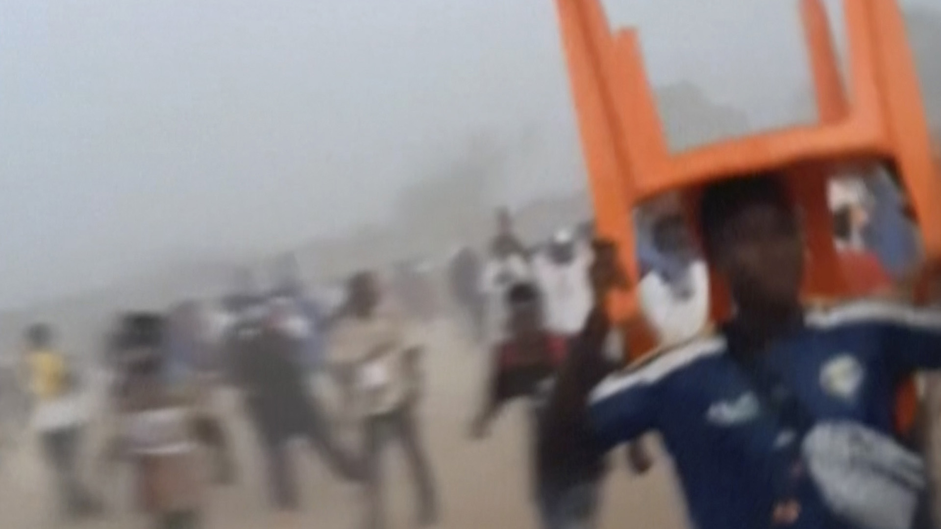 Sur cette image tirée d'une vidéo fournie par Nimba Sports Zaly, un homme tient une chaise sur sa tête lors d'une bousculade, pendant un match de soccer au Stade de Nzérékoré, à Nzérékoré, en Guinée, le dimanche 1er décembre 2024. 