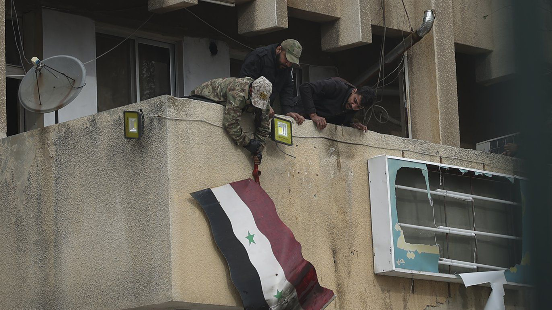 Des combattants de l'opposition syrienne retirent le drapeau du gouvernement syrien d'un bâtiment officiel à Salamiyah, à l'est de Hama, en Syrie, le samedi 7 décembre 2024. 