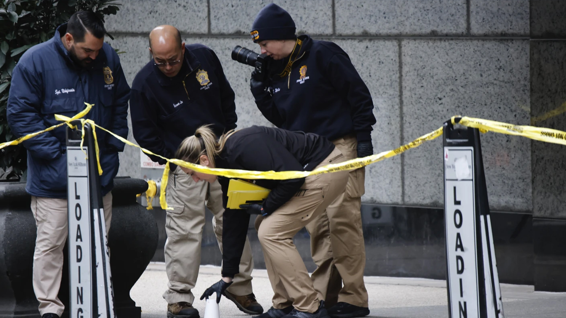 Des membres de l'unité de la police de New York  de la police de New York ramassent des coupelles où se trouvent les balles à l'extérieur de l'hôtel Hilton  dans le centre de Manhattan où  Brian Thompson, PDG de  UnitedHealthcare, a été tué par balle, mercredi 4 décembre 2024, à New York.  