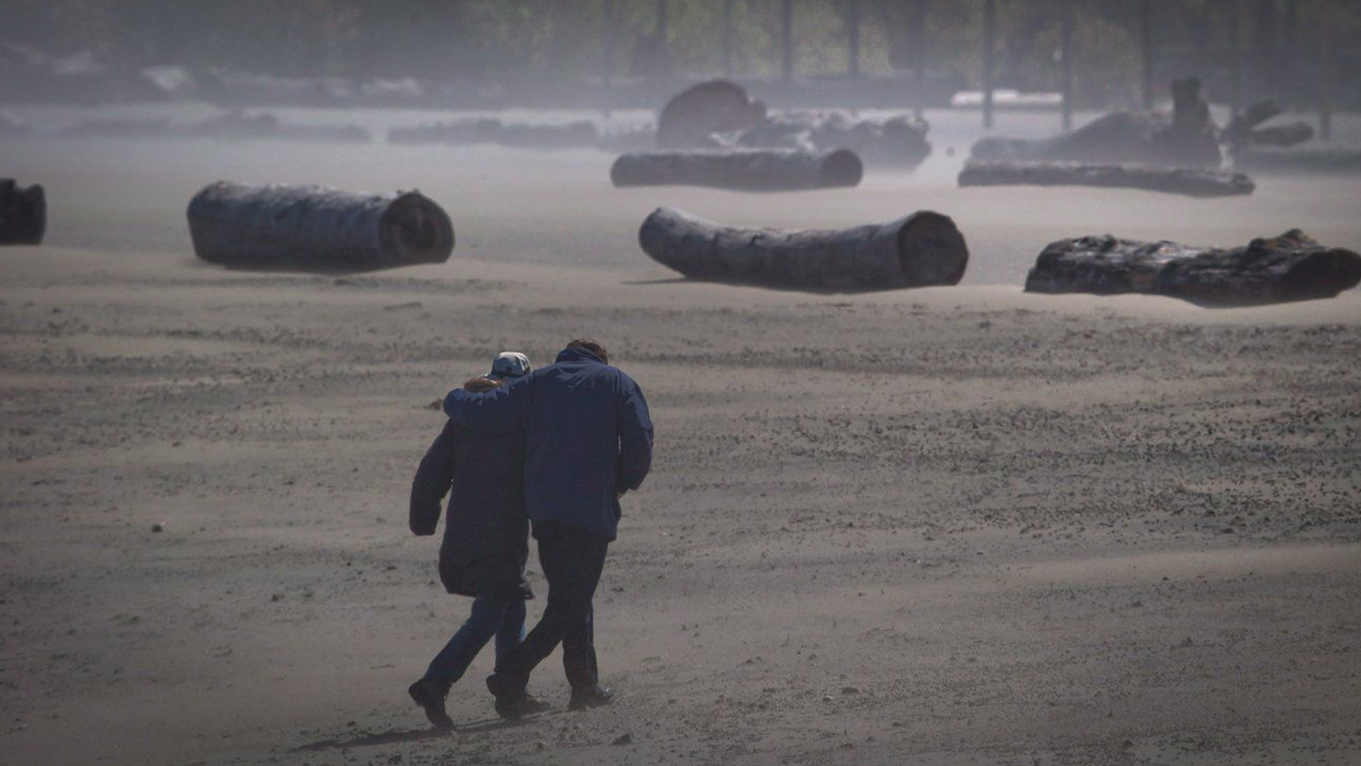 Des vents violents soulèvent du sable alors qu'un couple se promène le long de la plage Spanish Banks à Vancouver, en Colombie-Britannique, le lundi 29 avril 2013. 