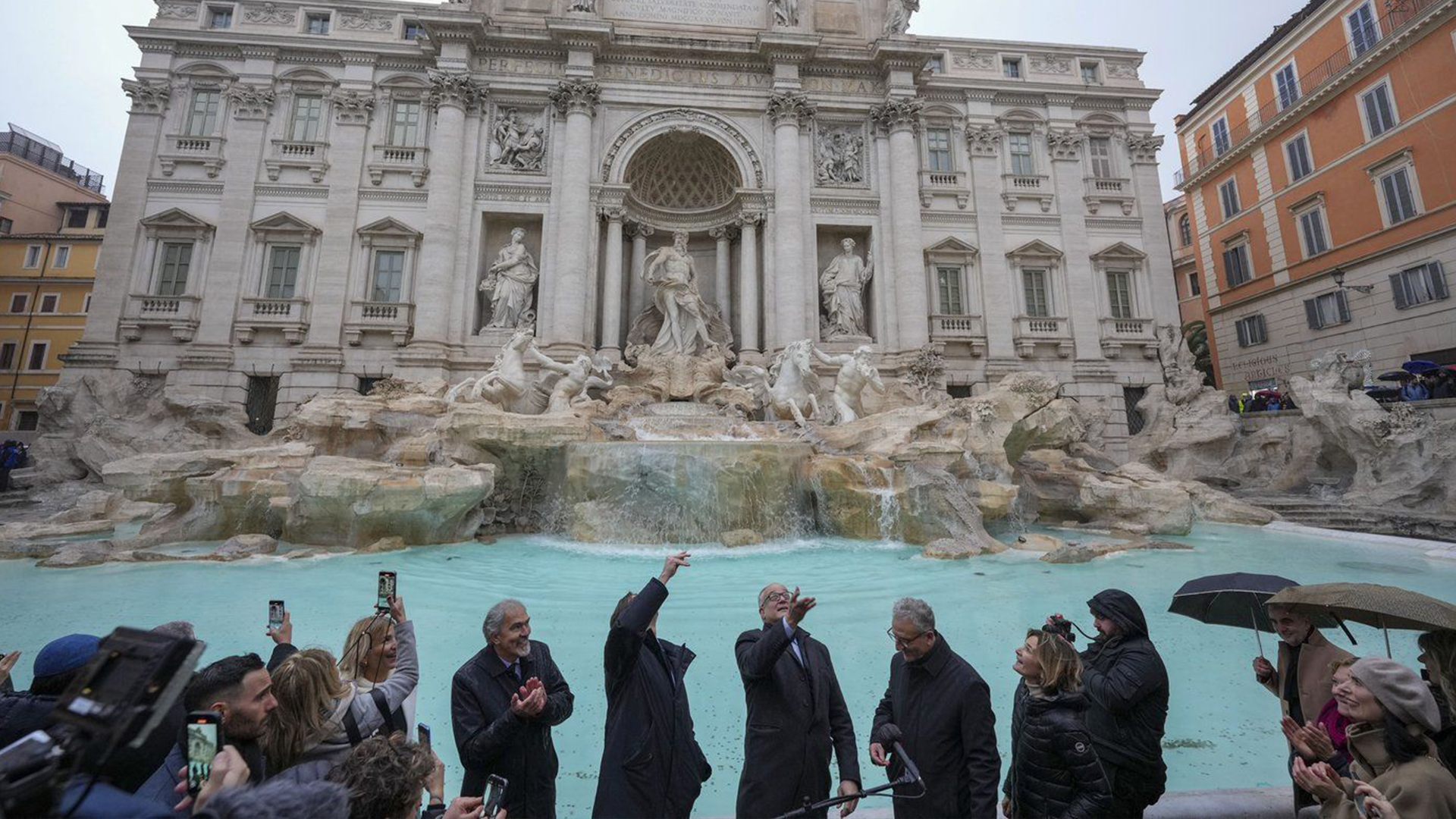 Le maire de Rome, Roberto Gualtieri, au centre, lance une pièce dans la fontaine de Trevi du XVIIIe siècle, l'un des monuments les plus emblématiques de Rome, alors qu'elle rouvre au public après avoir subi des travaux de maintenance, à Rome, le dimanche 22 décembre 2024. 