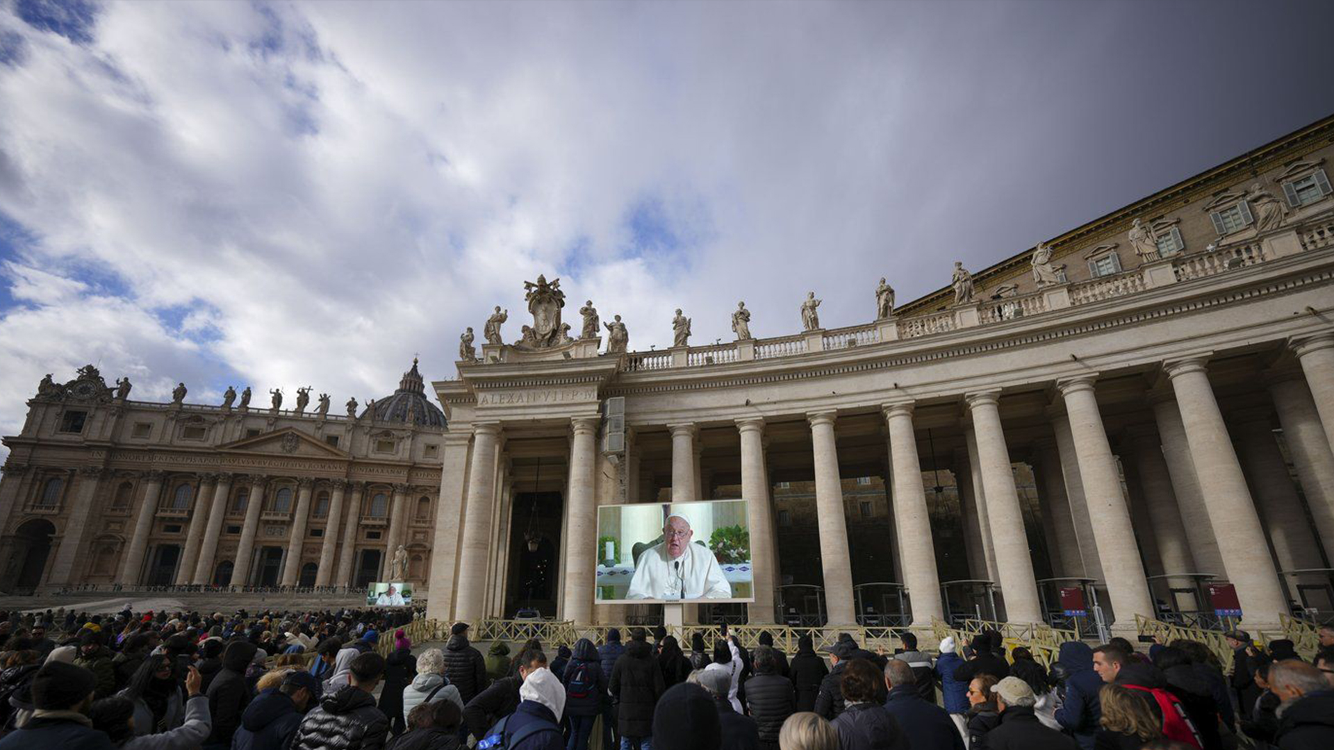 Les gens regardent un écran géant sur la place Saint-Pierre, au Vatican, montrant le pape François récitant la prière de l'Angélus de midi depuis sa résidence de Santa Marta, après avoir décidé de ne pas apparaître à la fenêtre de son studio donnant sur la place en raison d'un rhume persistant, dimanche 22 décembre 2024. 