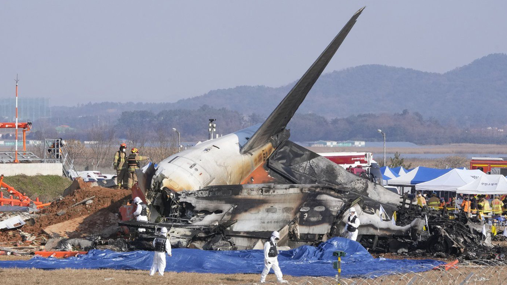 Des pompiers et des membres de l'équipe de secours travaillent près des décombres de l'écrasement d'un avion à l'aéroport de Muan en Corée du Sud, le 29 décembre 2024.