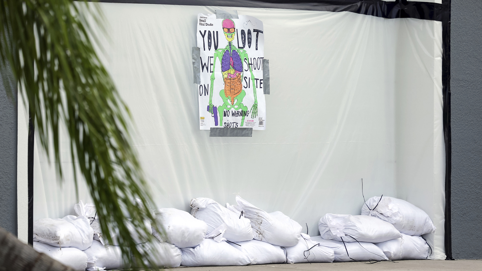 Le mardi 8 octobre 2024, à New Port Richey (Floride), un panneau met en garde les pillards sur une porte de garage recouverte de sacs de plastique et de sable en prévision de l'ouragan Milton. Photo : AP Photo | Mike Carlson